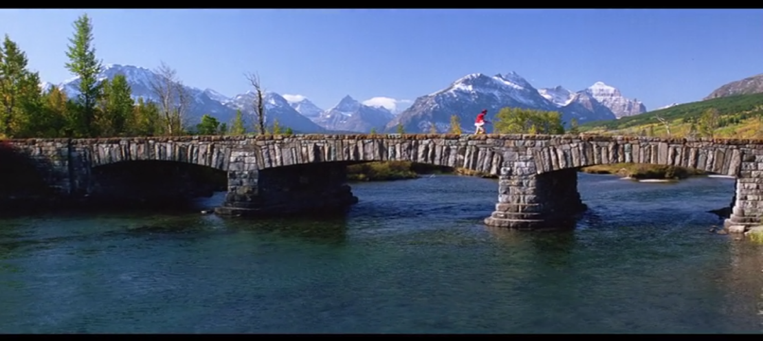 Forrest running across a stone bridge